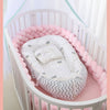 un couffin au milieu d'un berceau avec une tresse de lit bébé rose tout autour du berceau