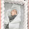 Un bébé dormant dans son berceau avec une tresse de lit bébé blanche autour de lui